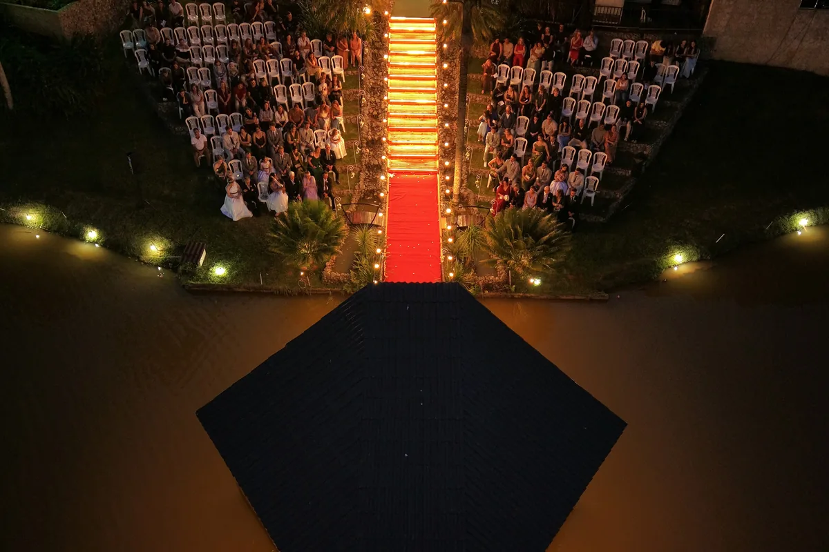 Escadaria iluminada à noite, com os convidados dos dois lados e o lago à frente