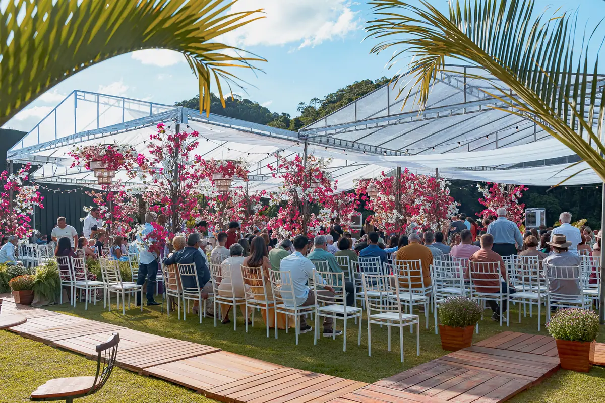 Cerimônia montada sob cobertura, com convidados e jardim em volta