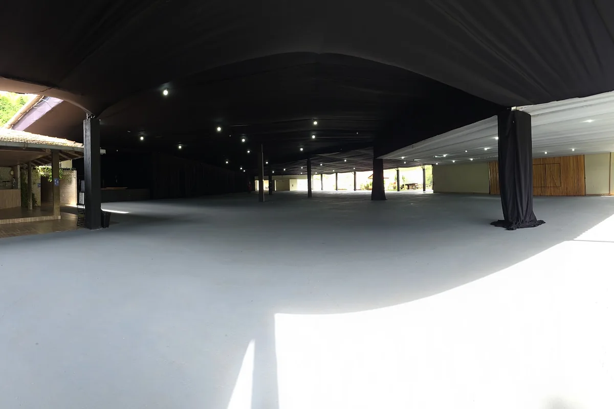 Salão coberto e vazio, mostrando a estrutura modular e o pé-direito