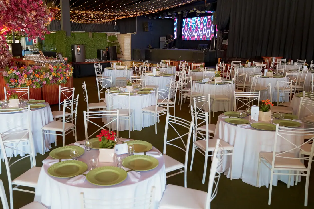 Salão montado com mesas redondas e telão para evento corporativo