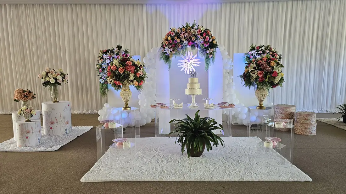 Cenário de crisma montado com painel de balões, flores e bolo